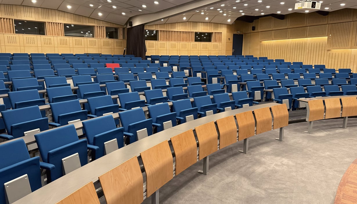 Tomt auditorium med blå sæder og træborde