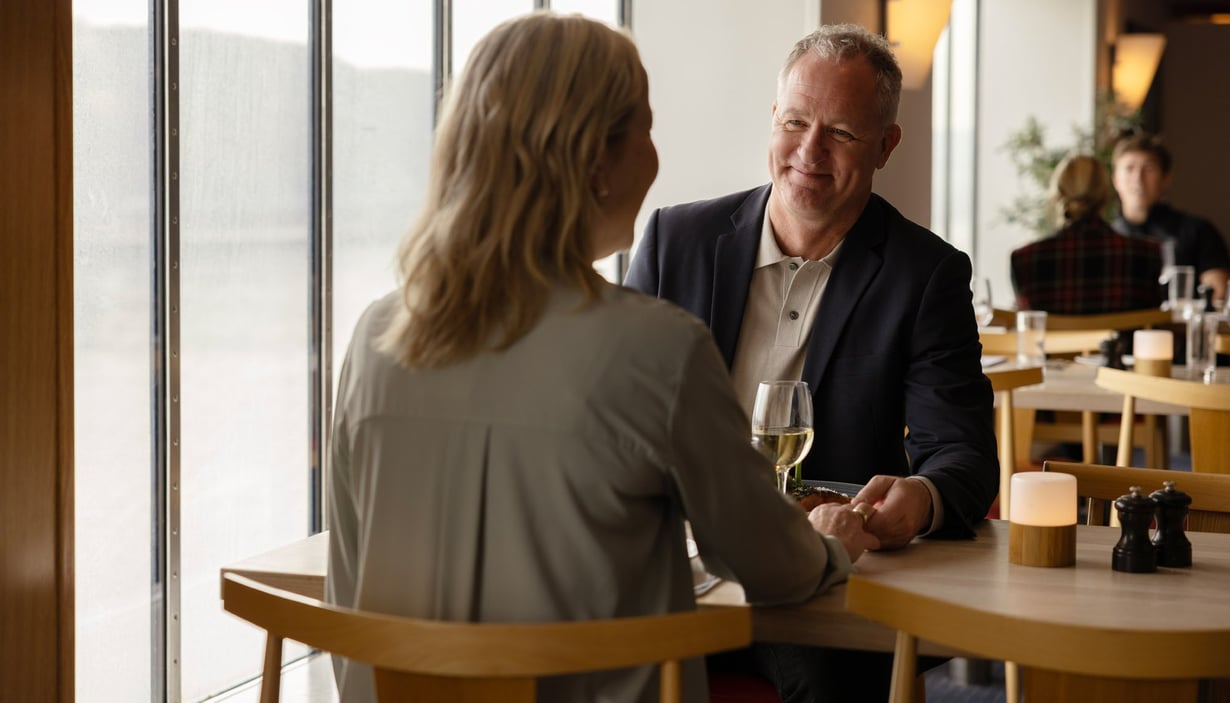 To personer sidder ved et bord i en restaurant og holder hænder.