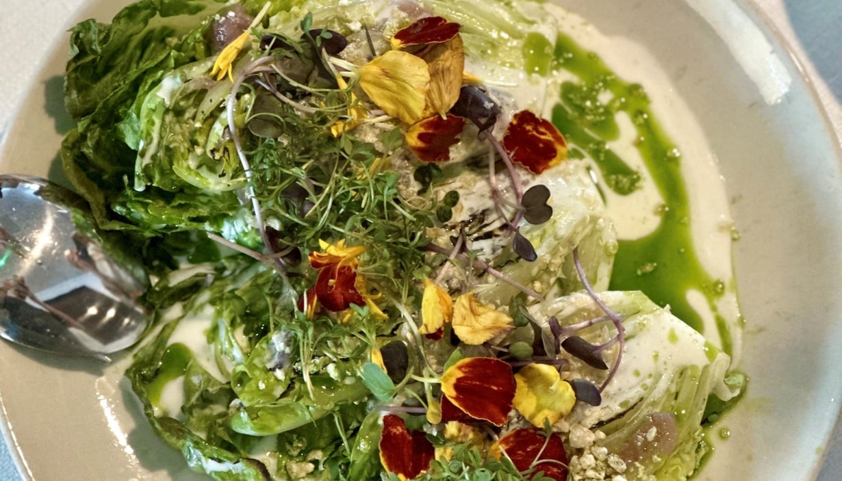 Tallerken med salat med forskellige grøntsager, mikrogrønt, spiselige blomster og grøn dressing