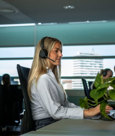 Person arbejder ved skrivebord med computer og hovedtelefoner