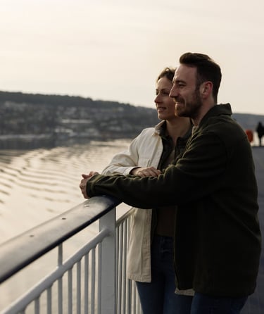 To personer står på et dæk og kigger ud over en vandmasse.