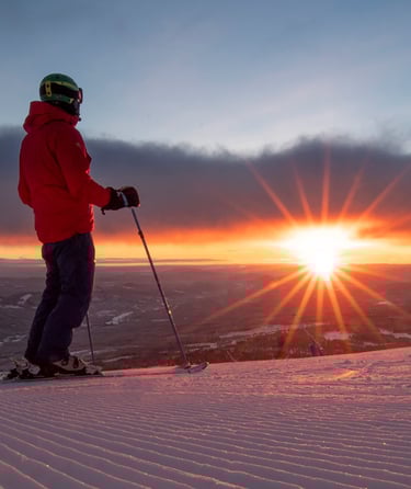 Person med skistave på en sneklædt bakke i Trysil ved solnedgang.