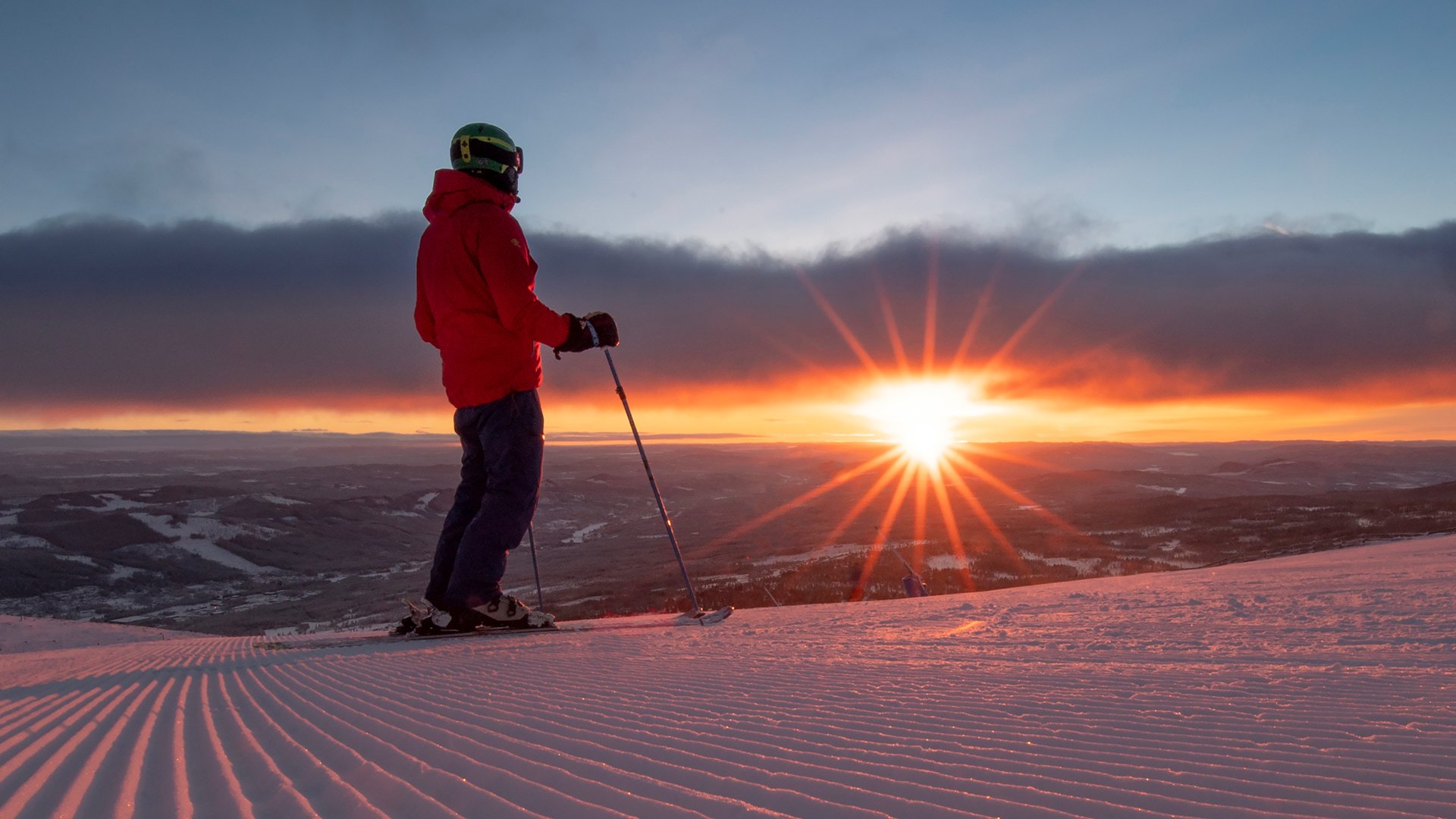 Person med skistave på en sneklædt bakke i Trysil ved solnedgang.