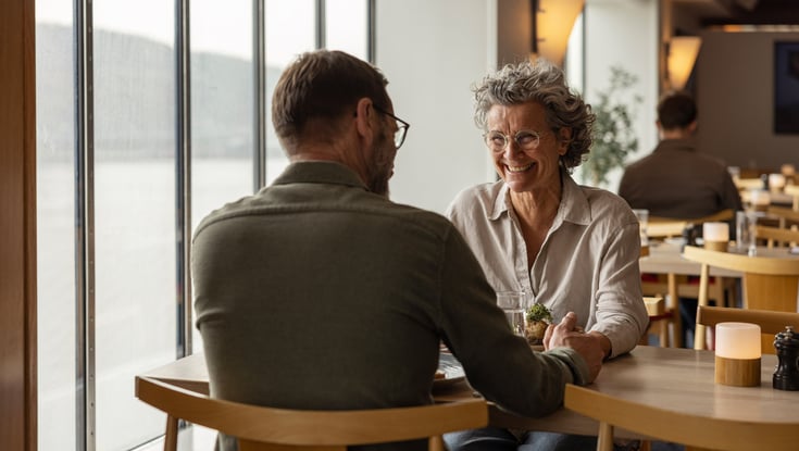 To personer sidder ved et bord i en restaurant og holder hænder