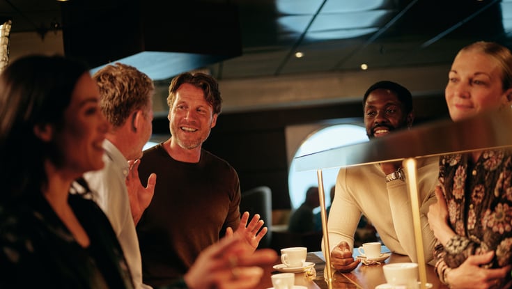 Gruppe mennesker der står rundt om en disk i en café.