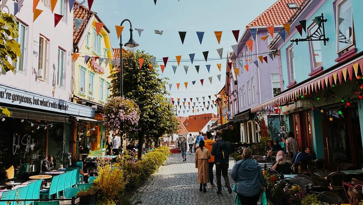 Farverig gade i Stavanger med caféer og flag.