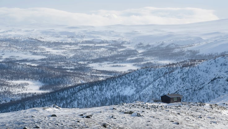 Sneklædt bjerglandskab med en hytte i Geilo.