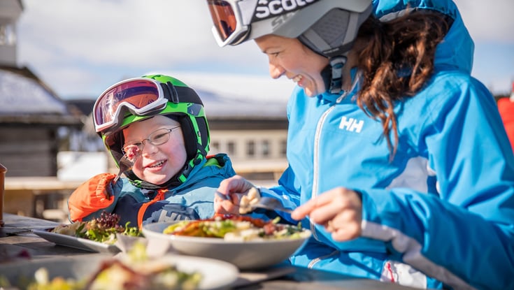 Familie spiser frokost på skibakken