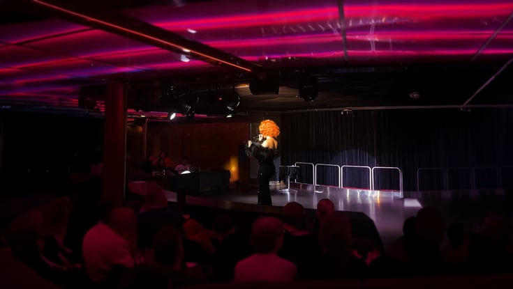 Performer med krøllet paryk på scenen.