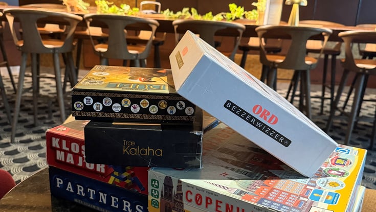 Stak af brætspil på et bord i en café.