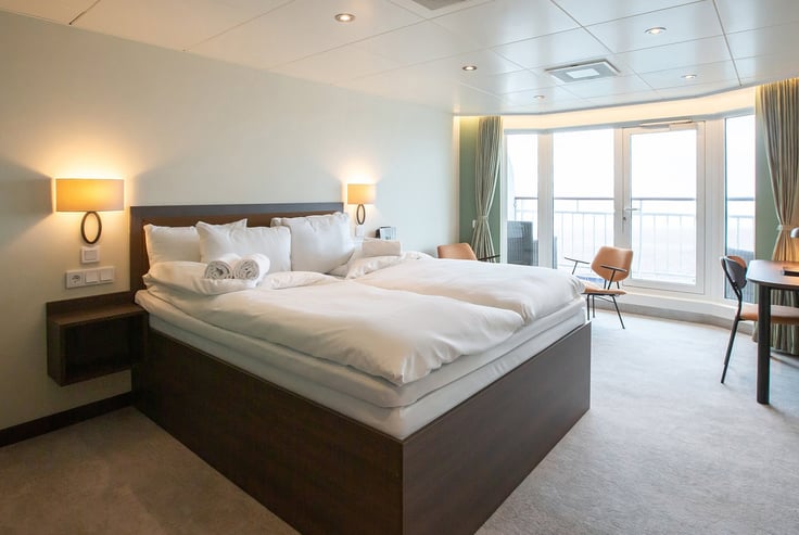 Moderne kahyt med stor seng, natborde og et vindue.