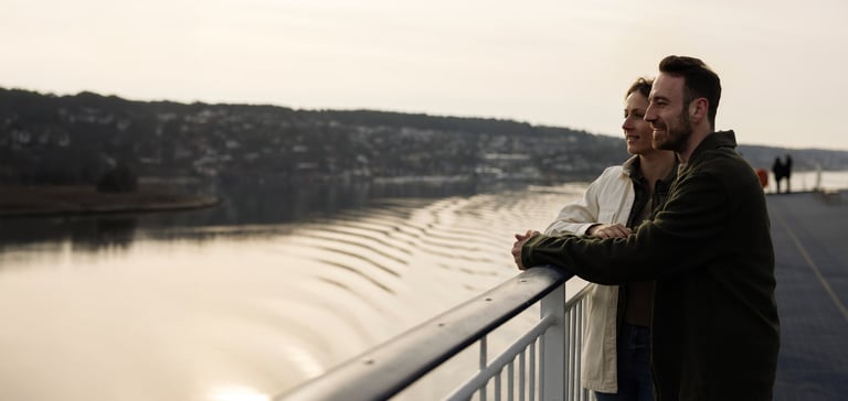 To personer står på en bro og kigger ud over en vandmasse.