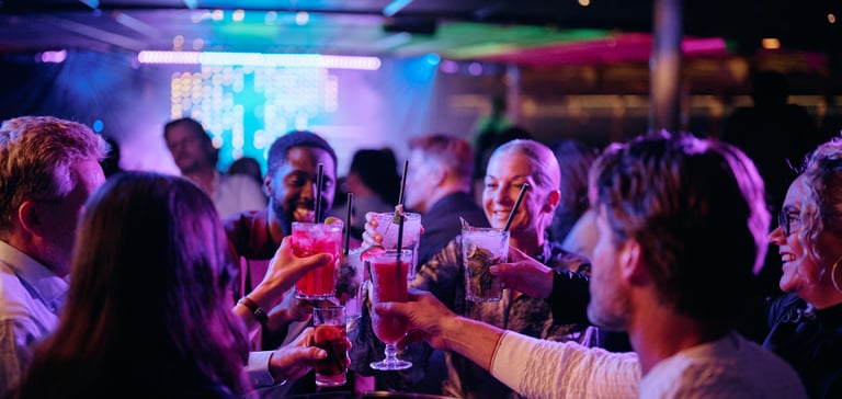 Folk fejrer på en livlig natklub med farverige lys og hævede glas