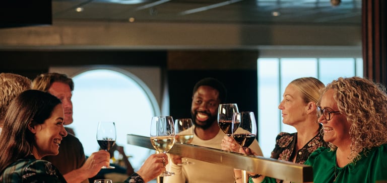 Gruppe mennesker der skåler med drikkevarer ved en bar.