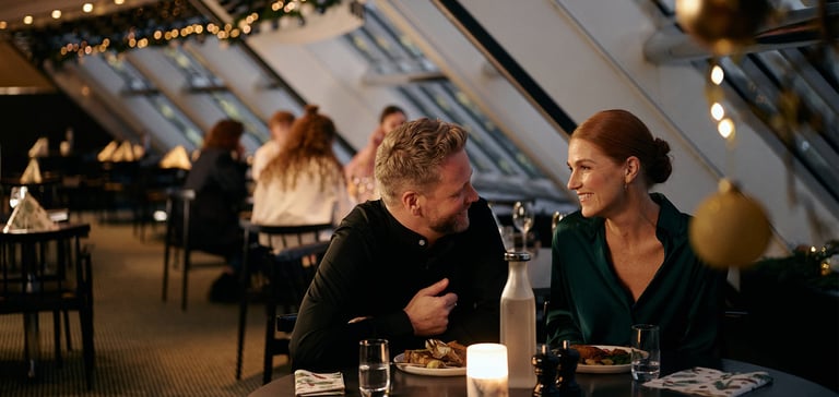 Folk der spiser på en restaurant med naturligt lys og dekorationer.