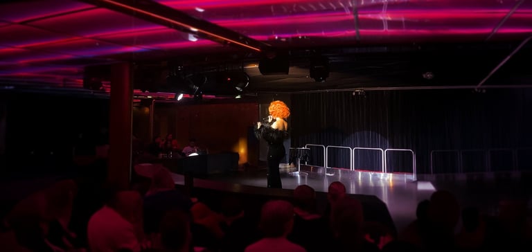 Performer med krøllet paryk på scenen.