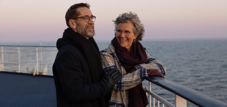 Ældre par med frakker der smiler på dækket