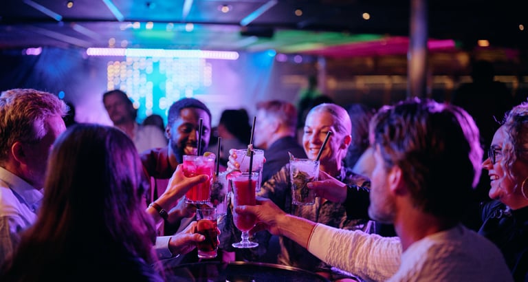 Folk fejrer på en livlig natklub med farverige lys og hævede glas
