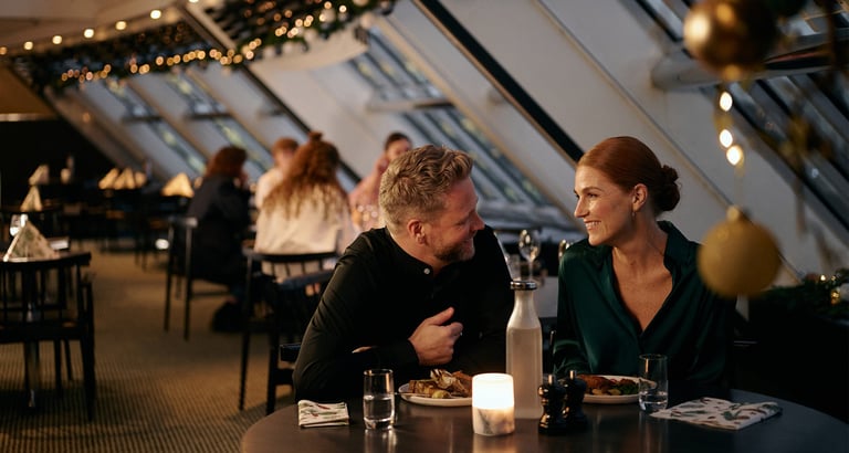 Folk der spiser på en restaurant med naturligt lys og dekorationer.