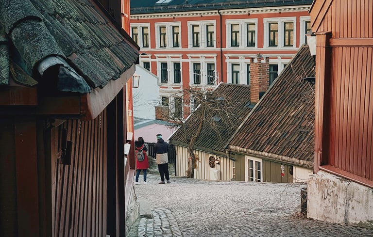 Smal brostensbelagt gade med traditionelle træhuse i Oslo.