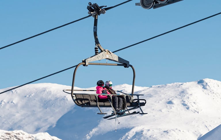Skilift med to personer på et snedækket bjerg.