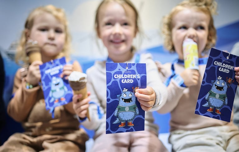 Tre børn, der holder "Children's Card"-hæfter med en tegneseriefigur i Matrosklubben.