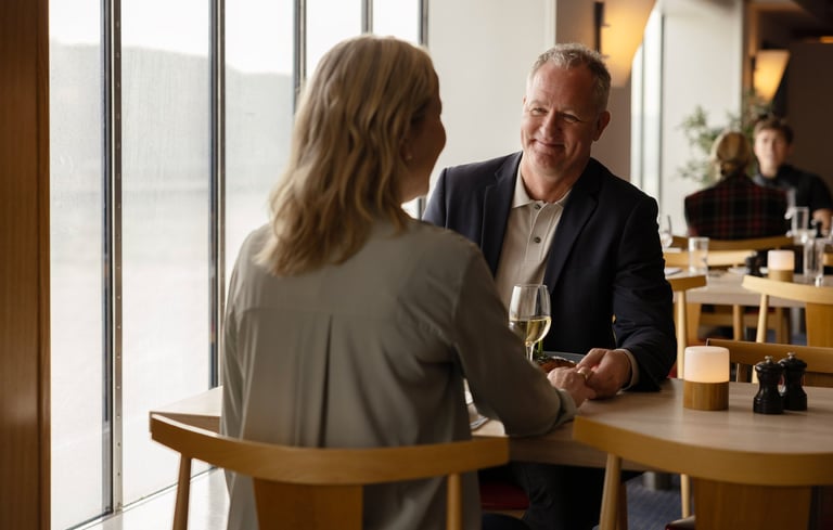 To personer sidder ved et bord i en restaurant og holder hænder.